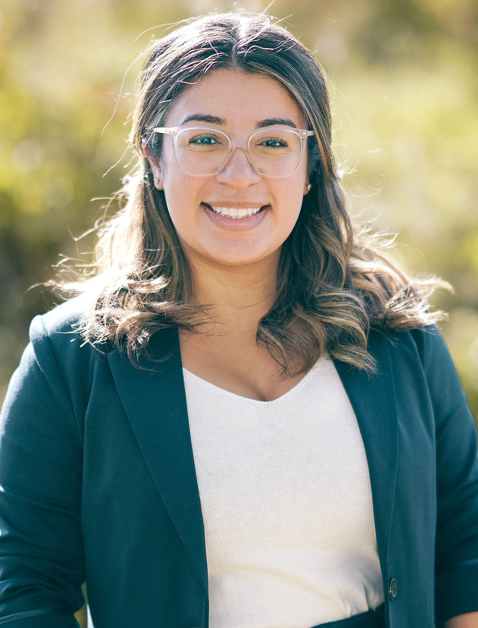 Adriana Ortiz-Lima, CPA auditrice et directrice, souriante à l’extérieur, par une journée ensoleillée.