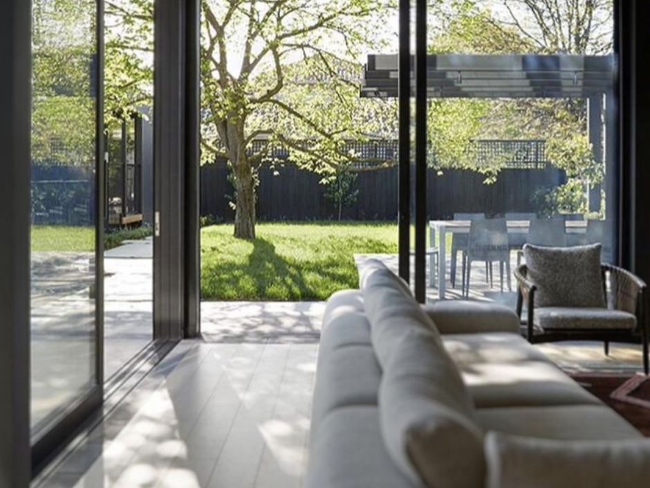 Bright and airy living room with floor-to-ceiling windows offering a seamless view of a lush garden, bringing the outdoors inside.