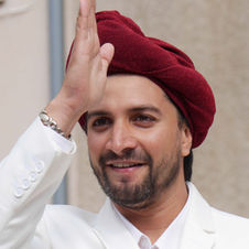 David Furlong groomed as a sickh in the character of Sittal, with an opulent white suit, a red turban, black beard and an expensive watch