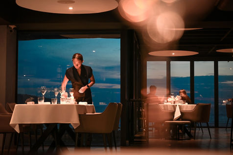 Professional waiter serving a fine dining dish at L’Arôme with elegance and attention to detail.