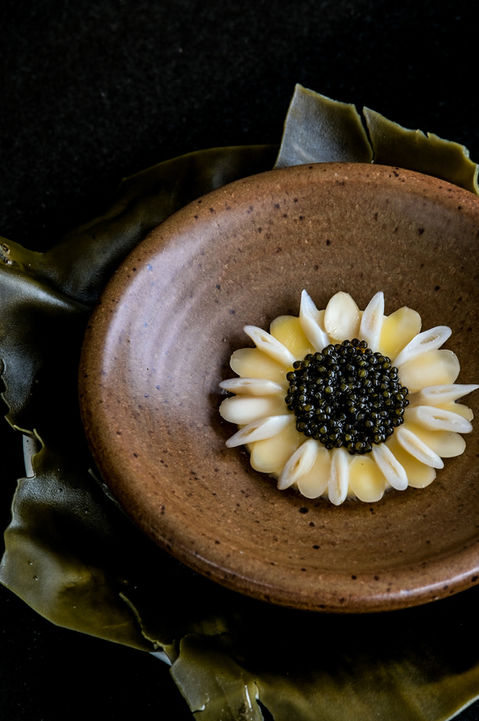 Close-up of L’Arôme by the Sea’s gourmet dish featuring razor clam with caviar and parmesan custard, plated elegantly on a fine dining ceramic plate.