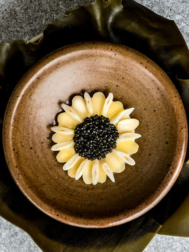 Close-up of L’Arôme by the Sea’s gourmet dish featuring razor clam with caviar and parmesan custard, plated elegantly on a fine dining ceramic plate.