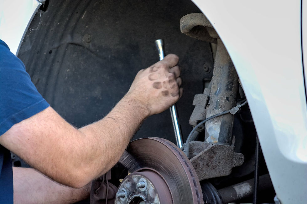Close-up of a mechanic's arms working on a car wheel and brake disc with a wrench