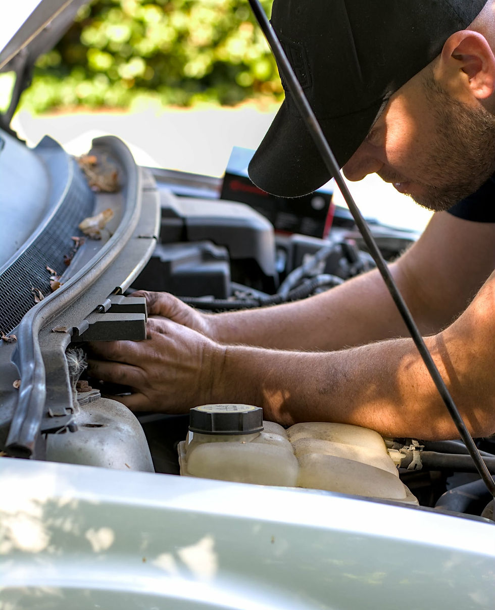 Portrait photo of a mobile mechanic working under the hood of a car, close-up on arms and engine bay