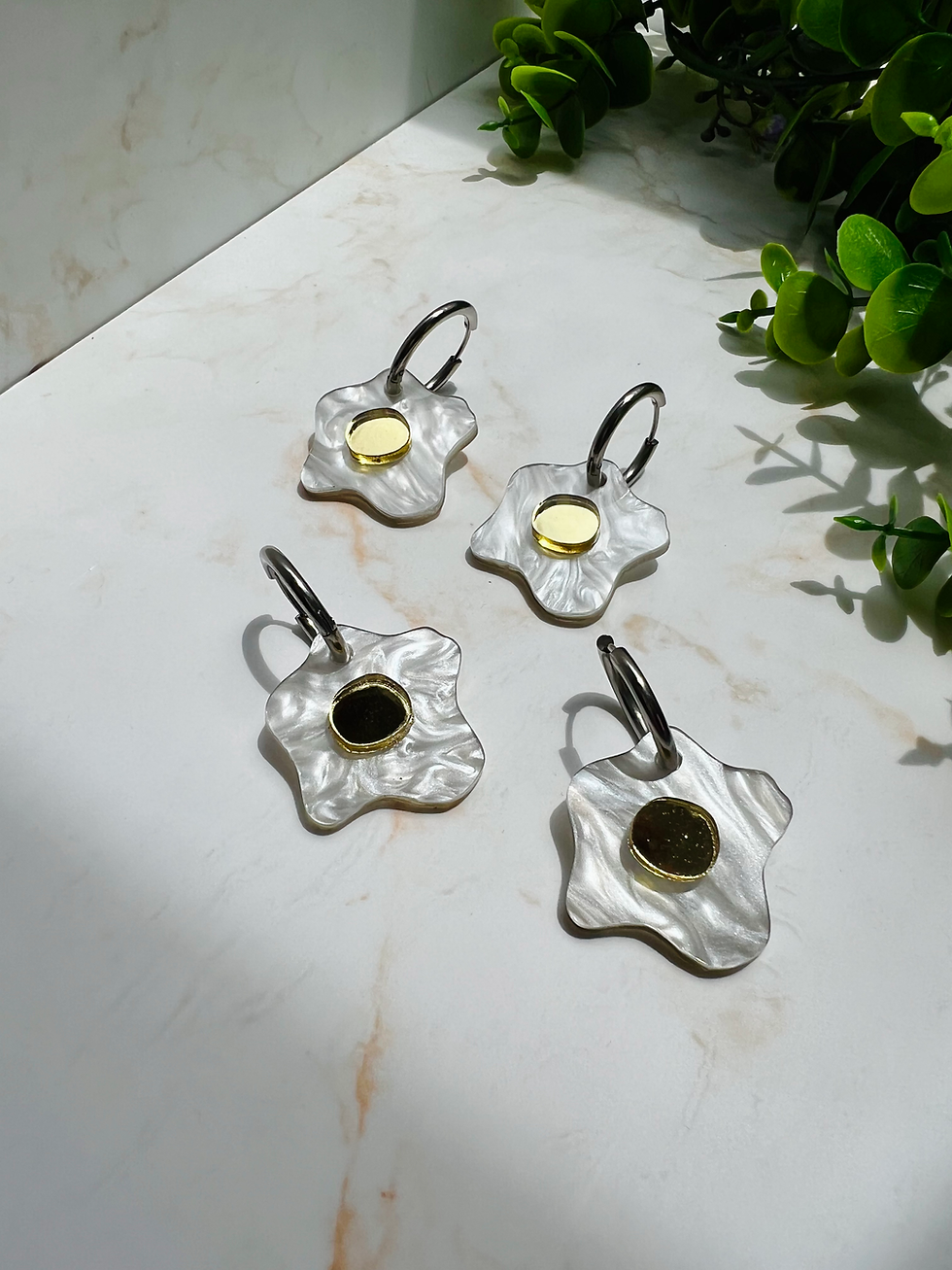 Miniatura: pendientes de huevo frito en blanco nacar y dorado sobre fondo de mármol 