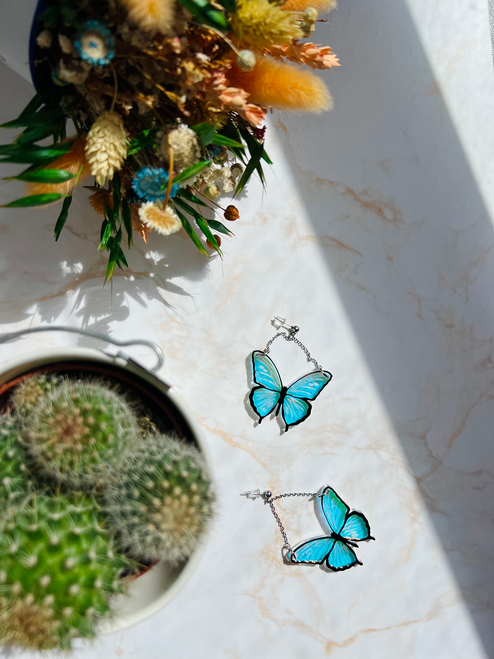 Miniatura: pendientes de mariposa con alas iridiscentes y perfil en negro junto a flores