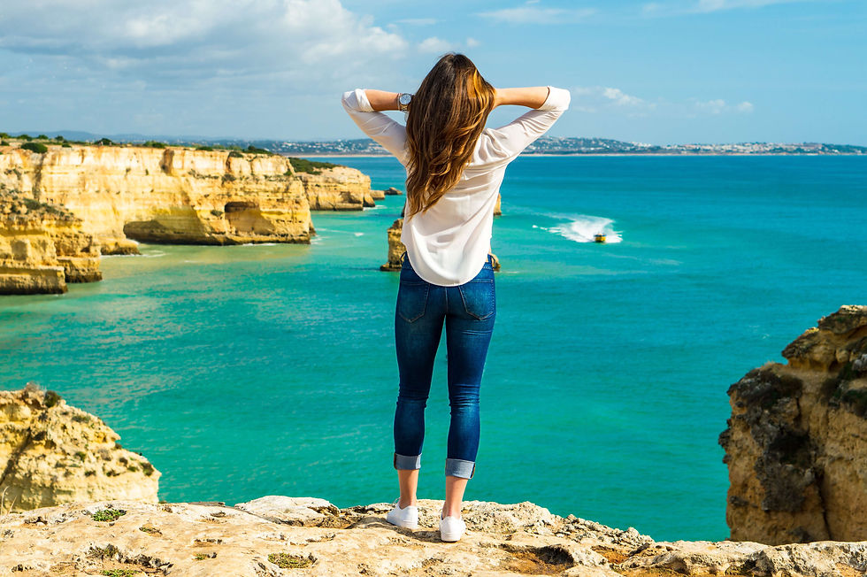 Woman standing on a cliff in lagos portugal