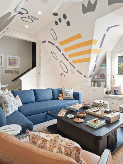 Wide angle playroom view with window seat, blue sectional and leather swivel chair