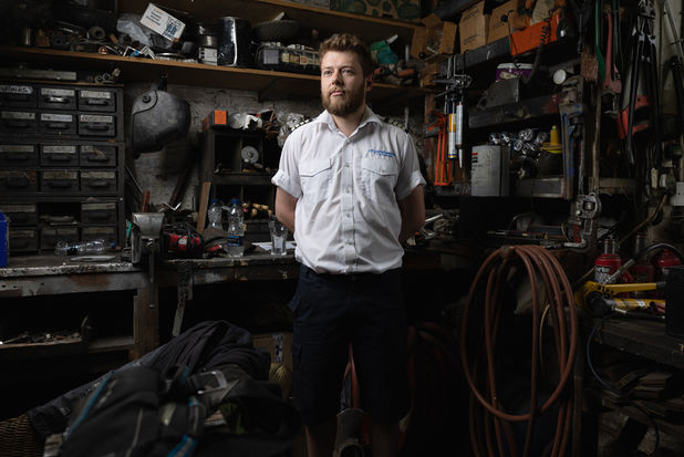 a ships captain poses in the ships workshop. He is surrounded by tools and spare parts