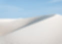 a cream colored sand dune beneath a blue sky