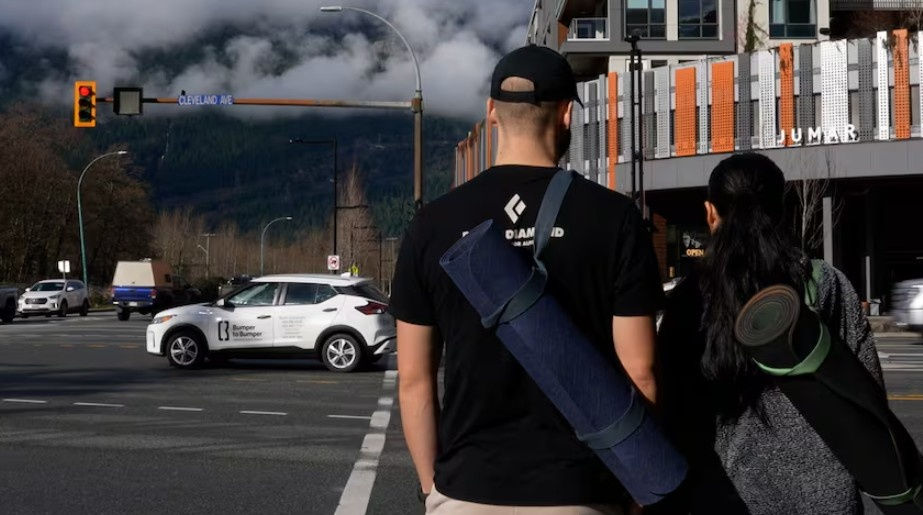 Two Squamish residents cross busy Cleveland Avenue intersection near Jumar building where speed limit drops to 30 km/h in February 2026