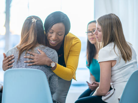 A group of young women sitting in a circle with two hugging.