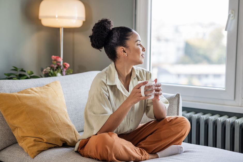 A young woman looking out the window with a mug