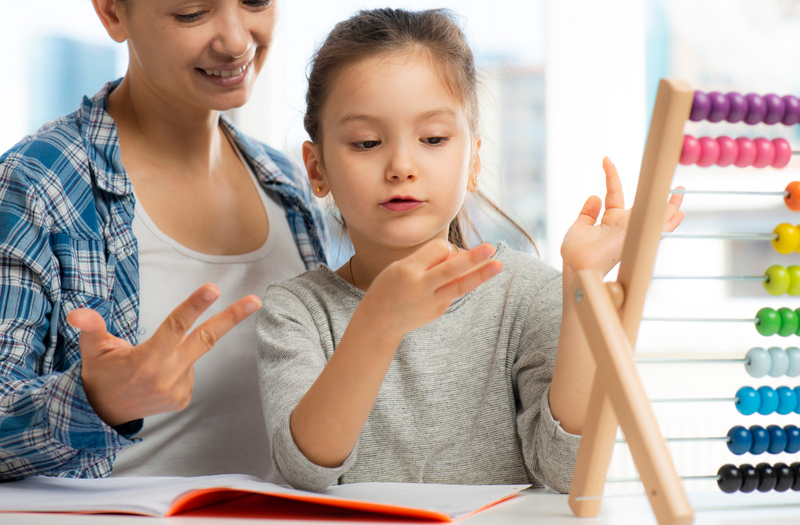 Une maman aide son enfant dans ses devoirs de mathématiques en utilisant des ressources pédagogiques
