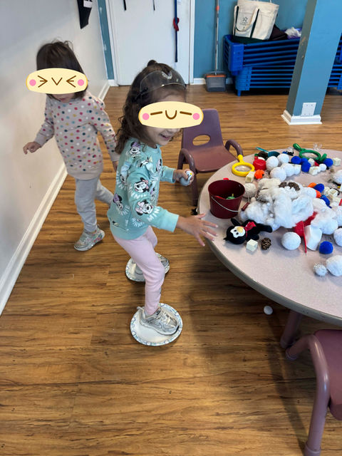 malvern academy students balancing on paper plates while playing near a table filled with winter-themed sensory toys and crafts.