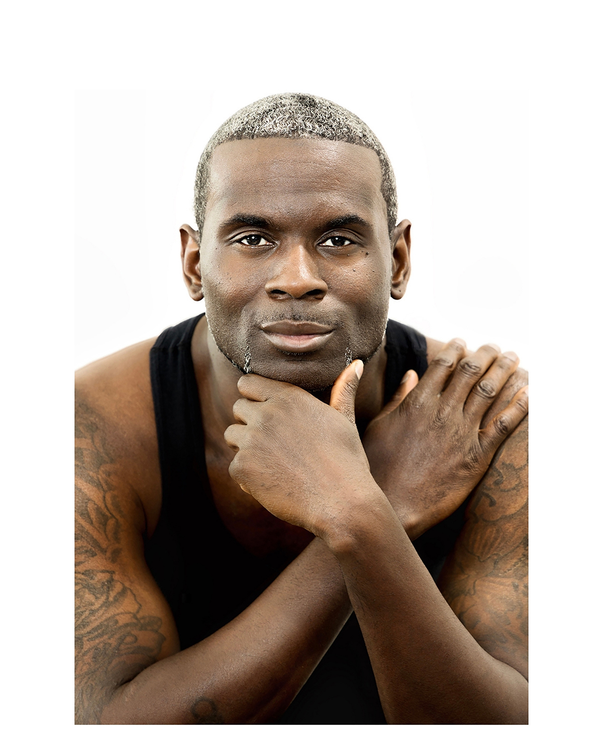 Dramatic studio portrait of a muscular man with a thoughtful pose, by Tina Dwyer Photography
