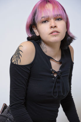 Acting headshot of a young woman with tattoos and a black top with a direct gaze, by Tina Dwyer Photography