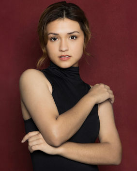 Studio portrait of a young woman in a black turtleneck with a warm expression, photographed by Tina Dwyer Photography