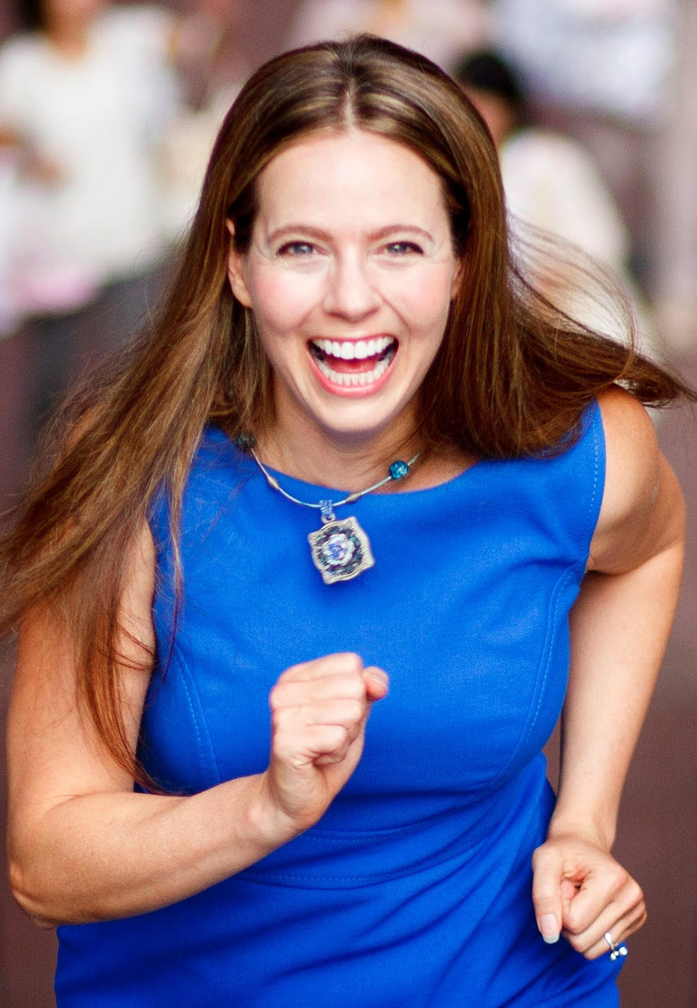 Soness Stevens - woman in blue dress posed as running towards camera with an open mouth smile