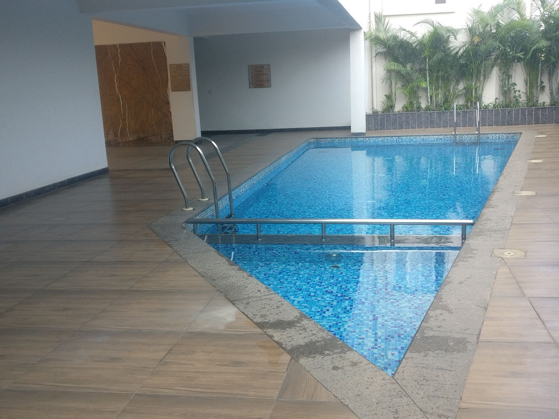 "Sparkling pool view at Mims Habitat, surrounded by lounge chairs and palm trees."