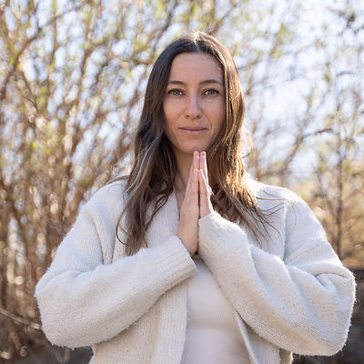 Portrait of Milena Re. A young woman smiling and in prayer position, with her hands together in front of her chest. Wearing white clothes.
