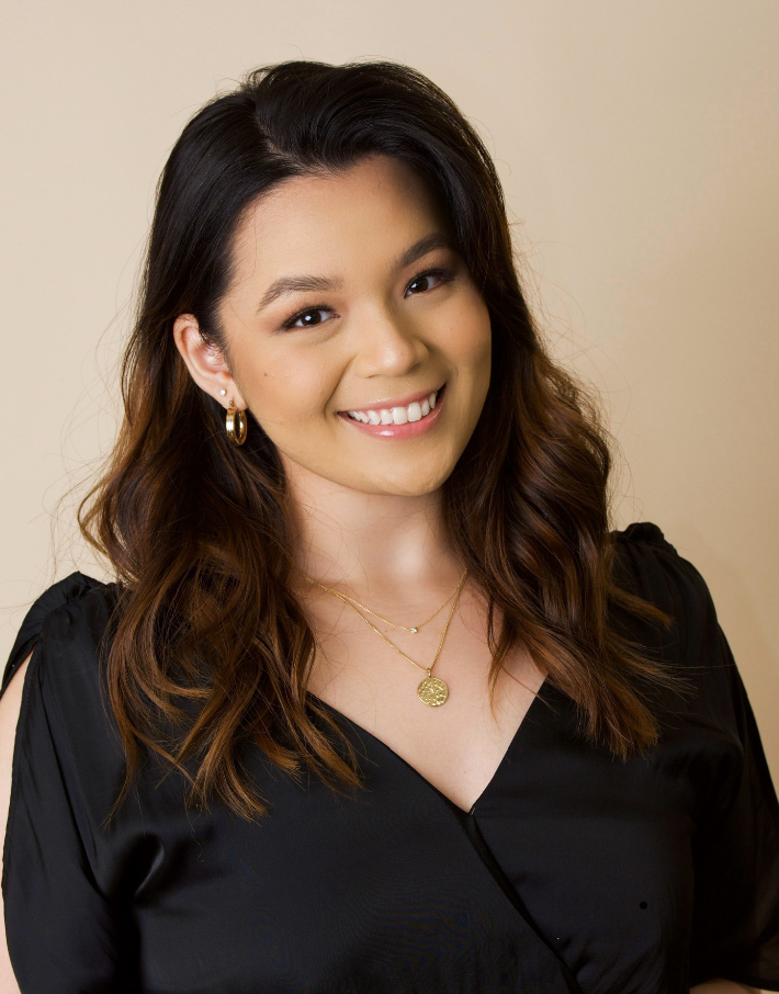 Smiling Asian woman with dark hair and a black top, poses happily.