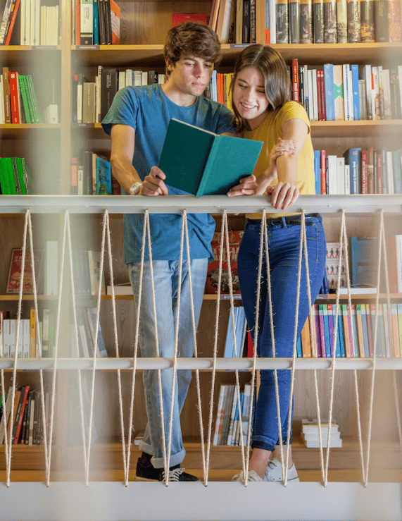 Two teenagers, standing together reading a book