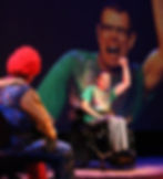 An actor in a wheelchair raises his arm in a cheer