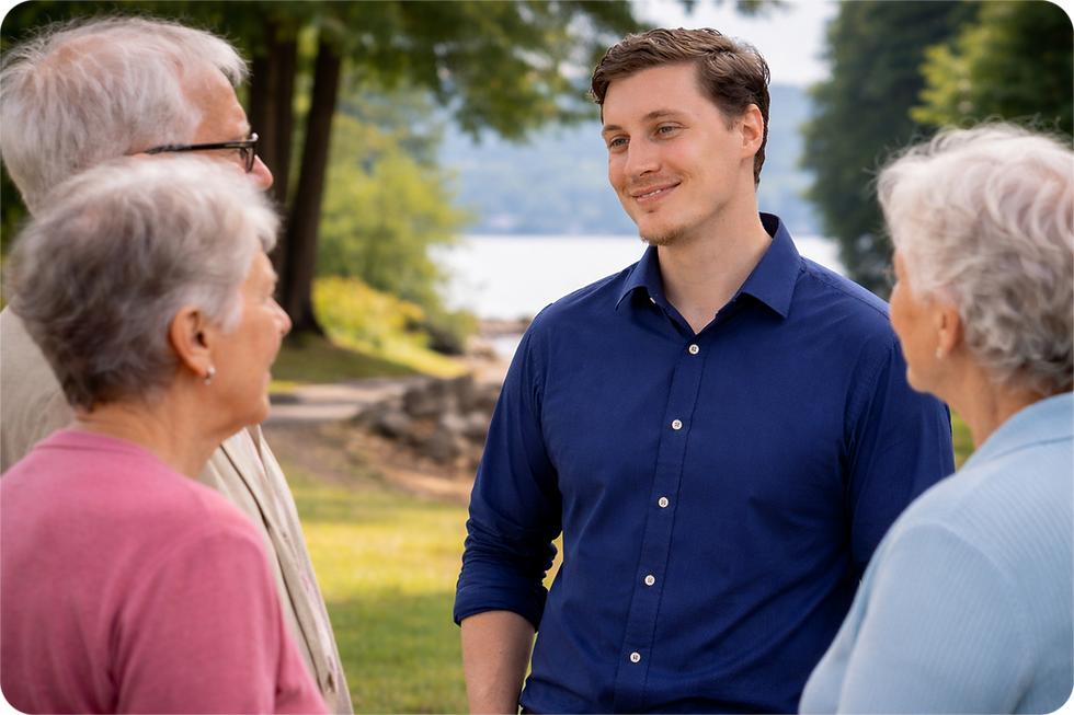 A smiling man in a blue shirt speaking with a group of seniors