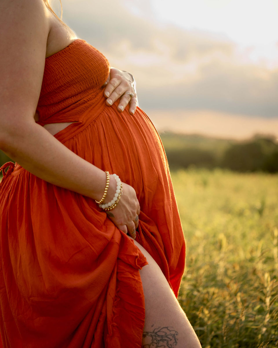A pregnant mom's bump is in focus against a gorgeous sunset at North Park in McCandless, PA.