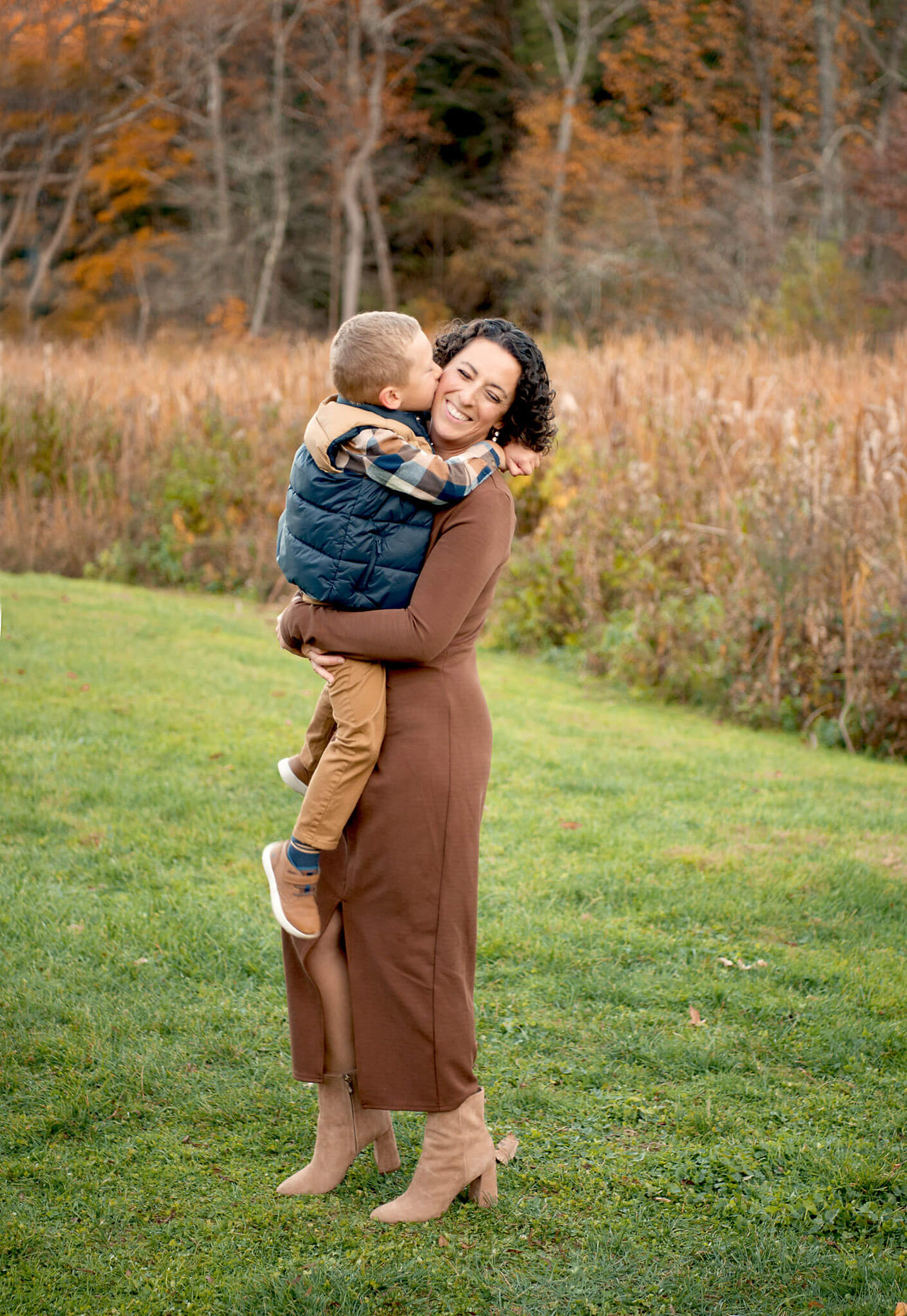 A mother holds her son and smiles as he kisses her on the cheek during family photos.