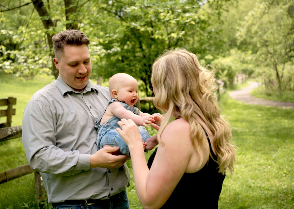 A young family of three is laughing and playing at Beechwood Farms Nature Reserve.