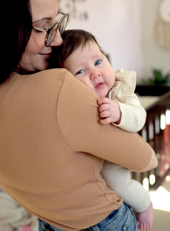 A mother is holding and kissing her newborn daughter.