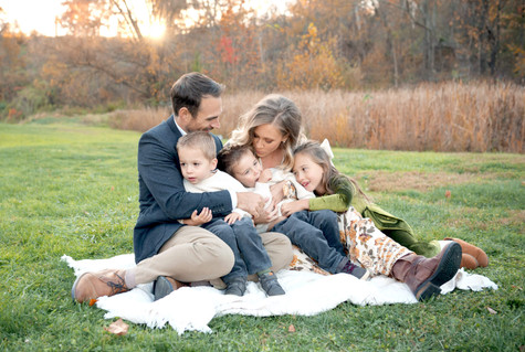 A family of five sit and laugh together at Emmerling Park during family photos. 