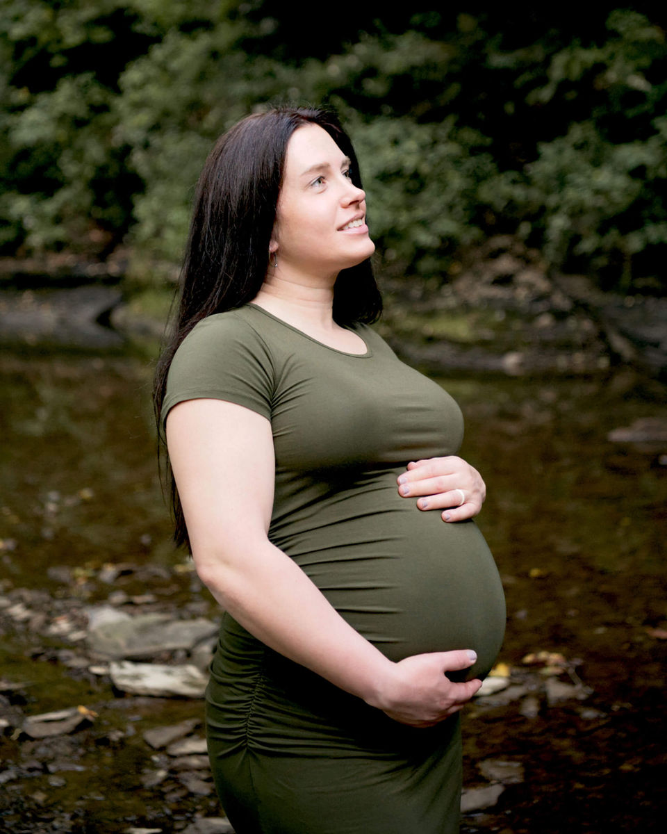 Radiant pregnant mother cradling her baby bump amidst the natural beauty of Crouse Run Nature Reserve, embracing the tranquility and connection with her unborn child.