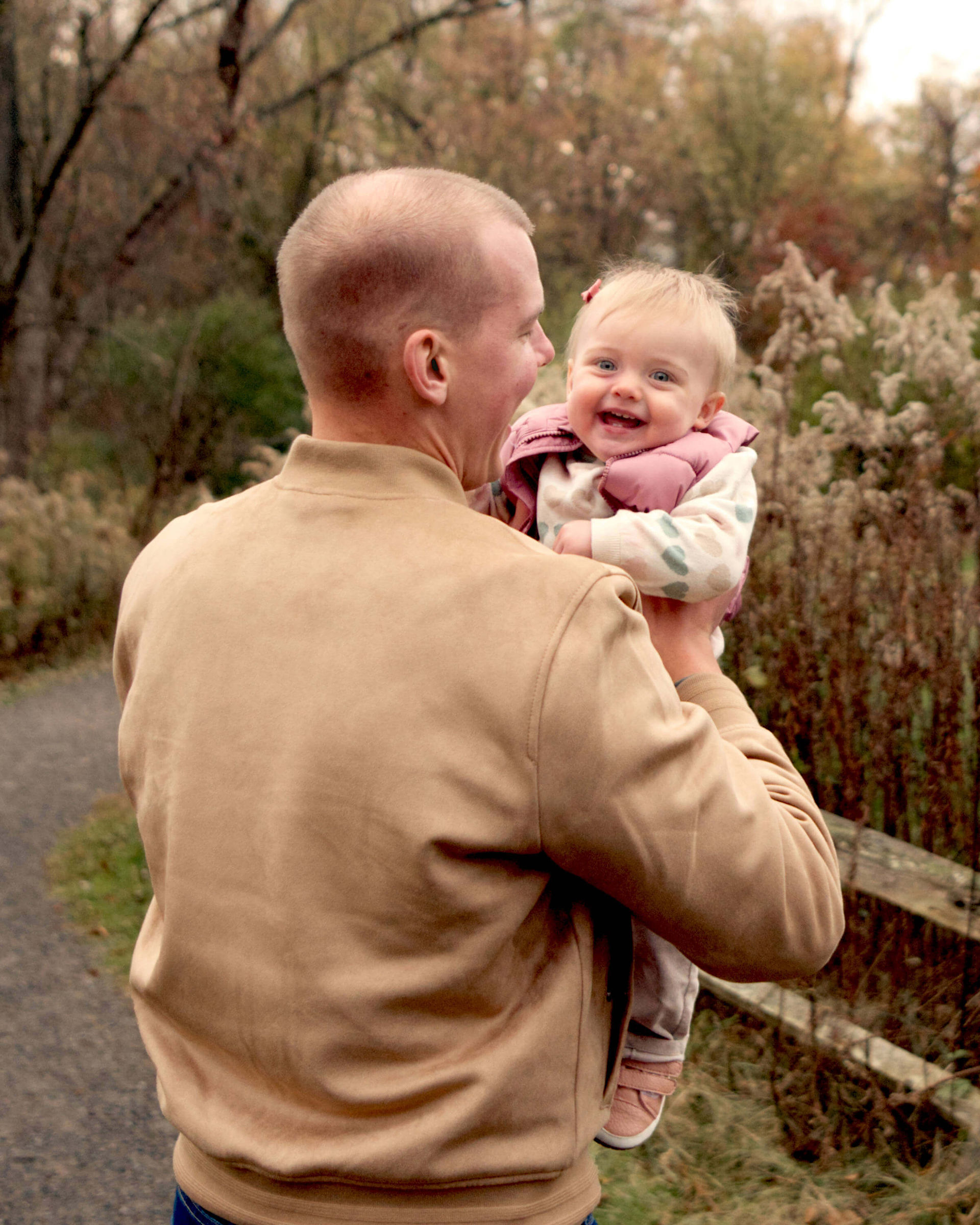 A father holds his daughter while his daughter laughs.