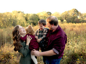 A family of four laughing and tickling each other while standing in Sewickley Heights Borough Park.