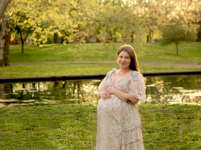 A pregnant mother smiles while holding her baby bump in front of Lake Elizabeth in Pittsburgh, PA.