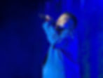 Man in blue suit singing with blue background