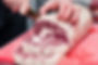stock-photo-closeup-macro-cook-s-hand-cut-ribeye-marbled-beef-steak-with-knife-on-red-plas