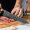 Thumbnail: Kiritsuke knife slicing red meat on a wooden board, showing Damascus blade detail