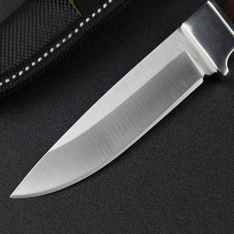 Detailed view of the high carbon steel blade on a fixed blade hunting knife, showing the sharpened edge and fine grind.