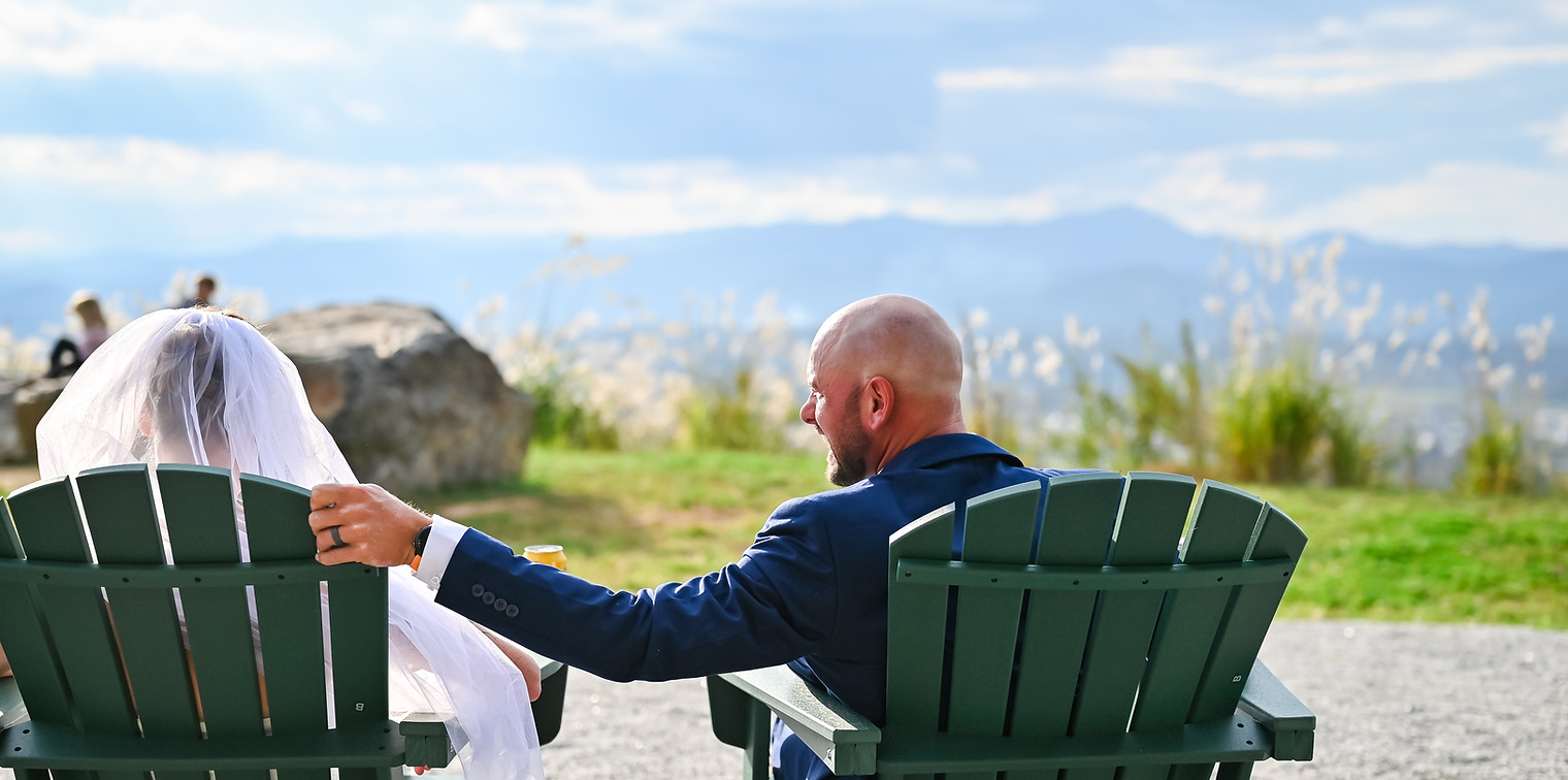 Bride and Groom sitting in chairs and looking at the view from the Wildnerness Campus.