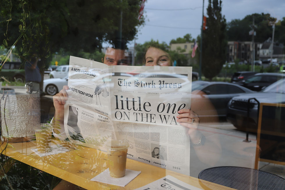 TR + Ava excitedly peek over a newspaper called "The Stork Press" and the headline "Little One On The Way" over coffee and through the window.