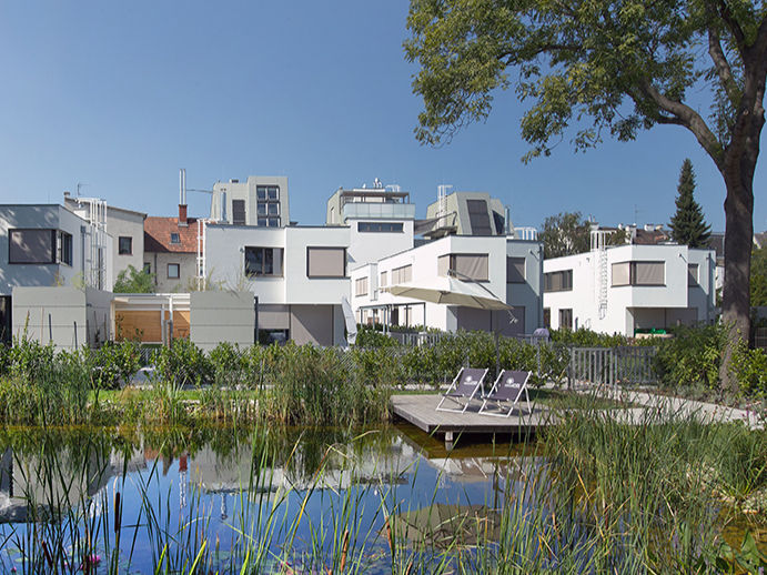 Naturteich mit Holzsteg und Liegen im Gartenbereich der Ville Verde Wohnanlage in Wien.