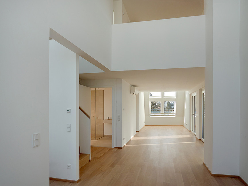 Offener Wohnbereich mit Galerie und bodentiefen Fenstern in der Ville Verde Wohnanlage.