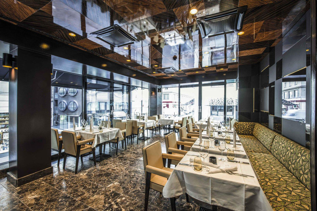 Hotel Lamée Restaurant mit gedeckten Tischen, Marmorboden und großen Fensterfronten.