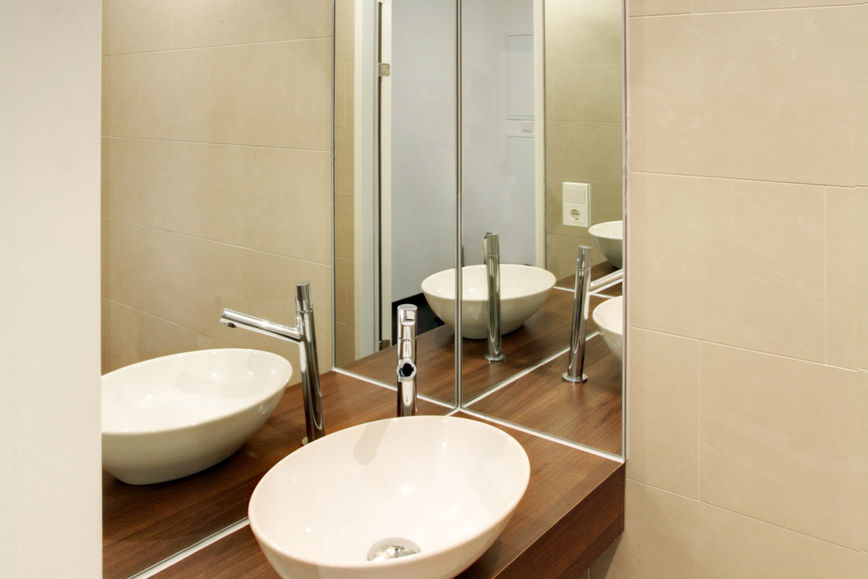 Modernes Badezimmer mit Aufsatzwaschbecken und Spiegelwand im Projekt The Greens.