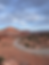 A road heading into the distance with red rock structures in the back. 