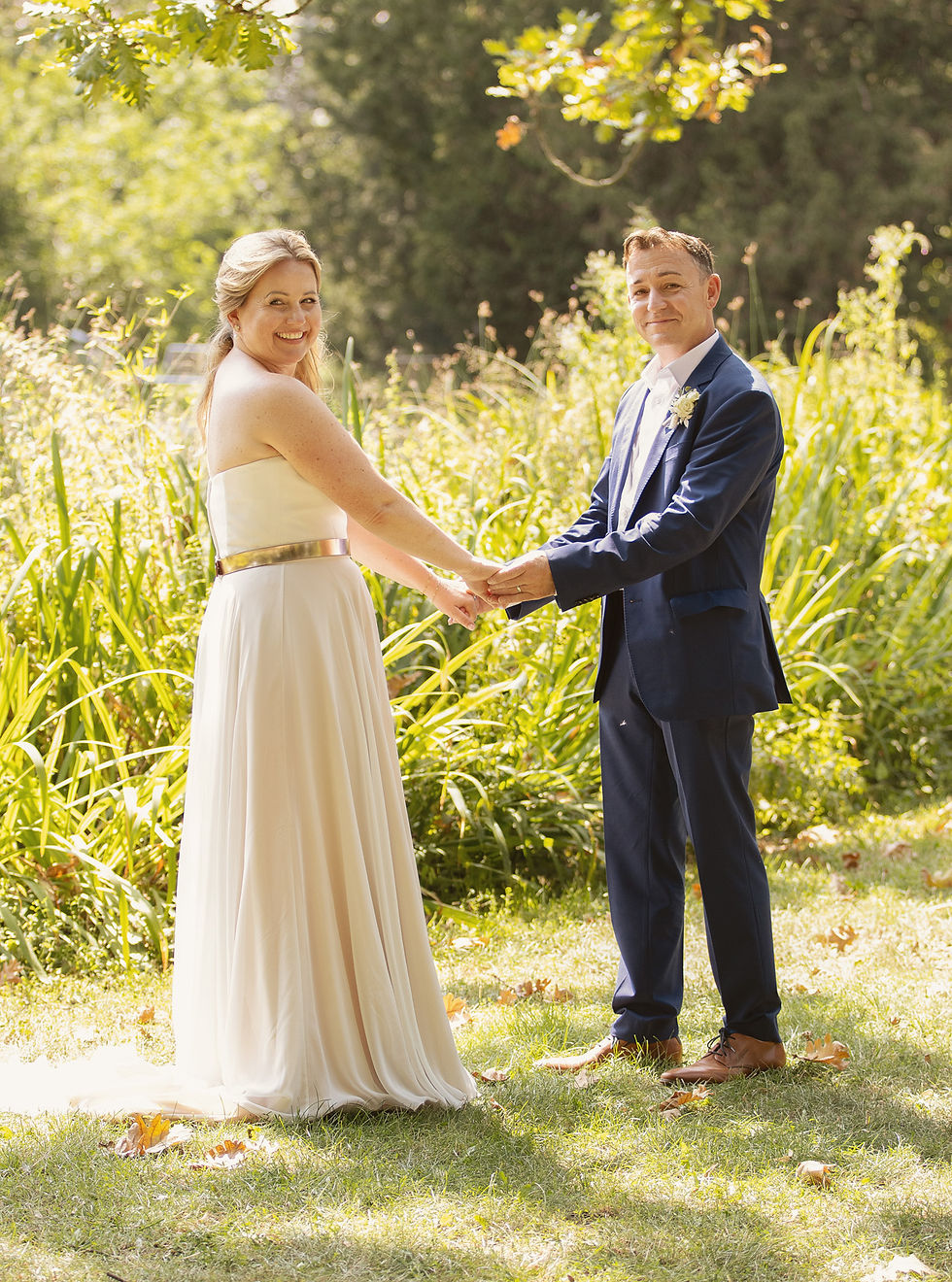 Hochzeitsfotografie in Frankfurt. Das Brautpaar hält sich an den Händen und steht vor grünen Pflanze